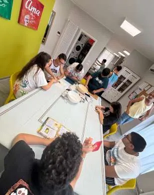 Ragazzi ed educatori attorno a un tavolo lungo, impegnati in un'attività di potenziamento delle autonomie