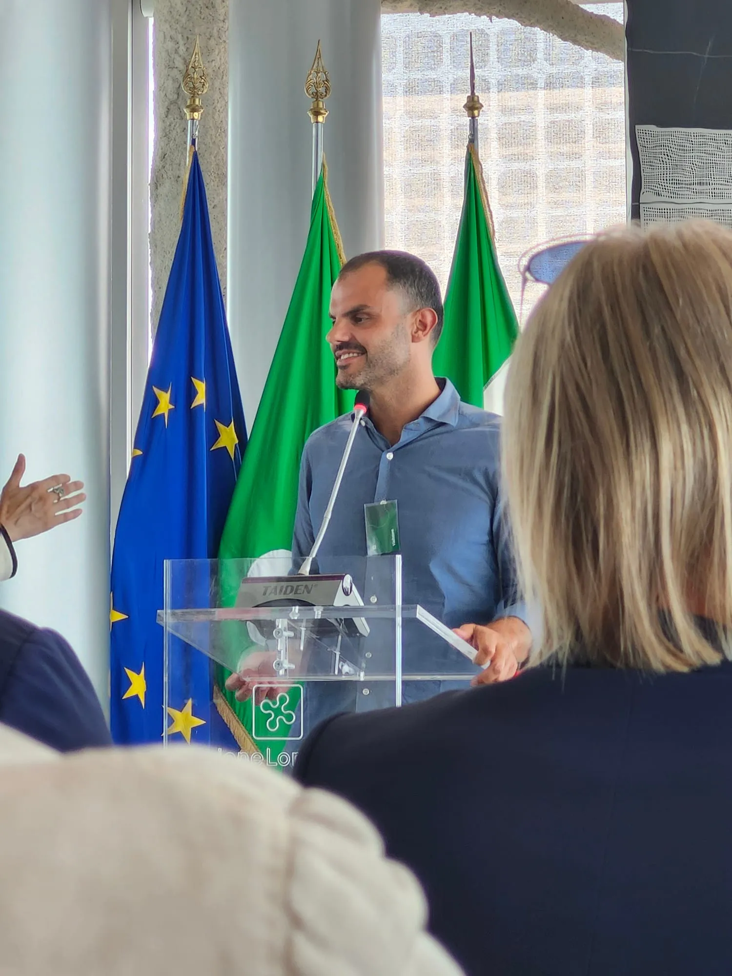Un relatore parla al leggio, visto fra il pubblico
