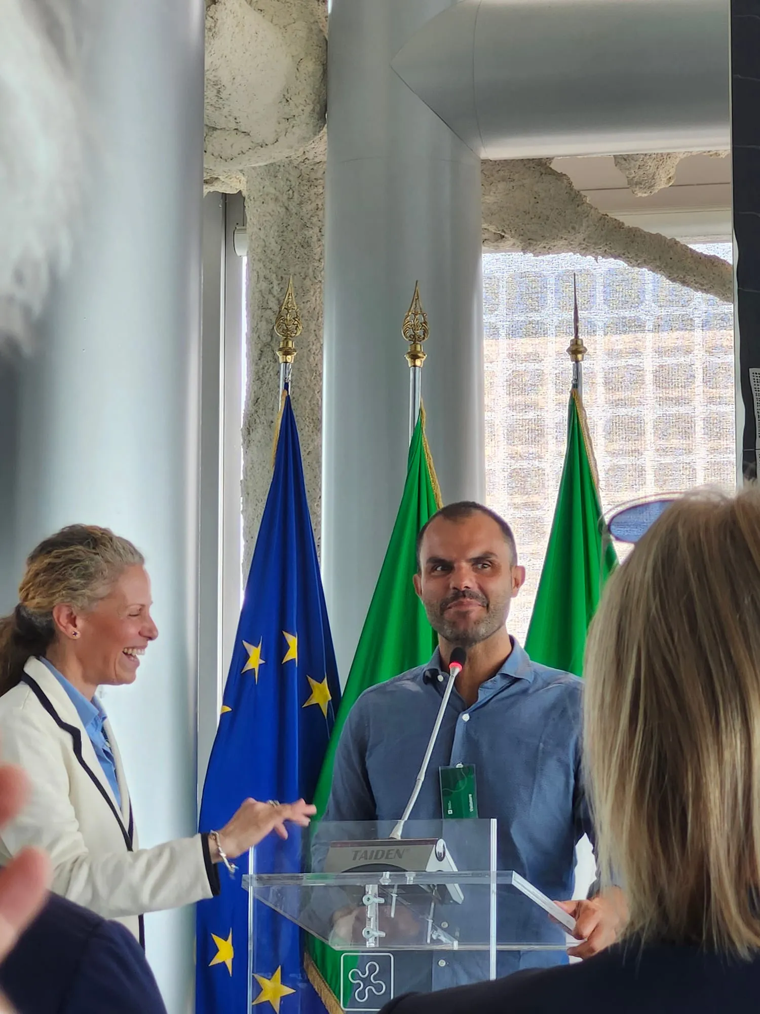 Lo stesso intervento in una ripresa più larga, con la moderatrice accanto al leggio