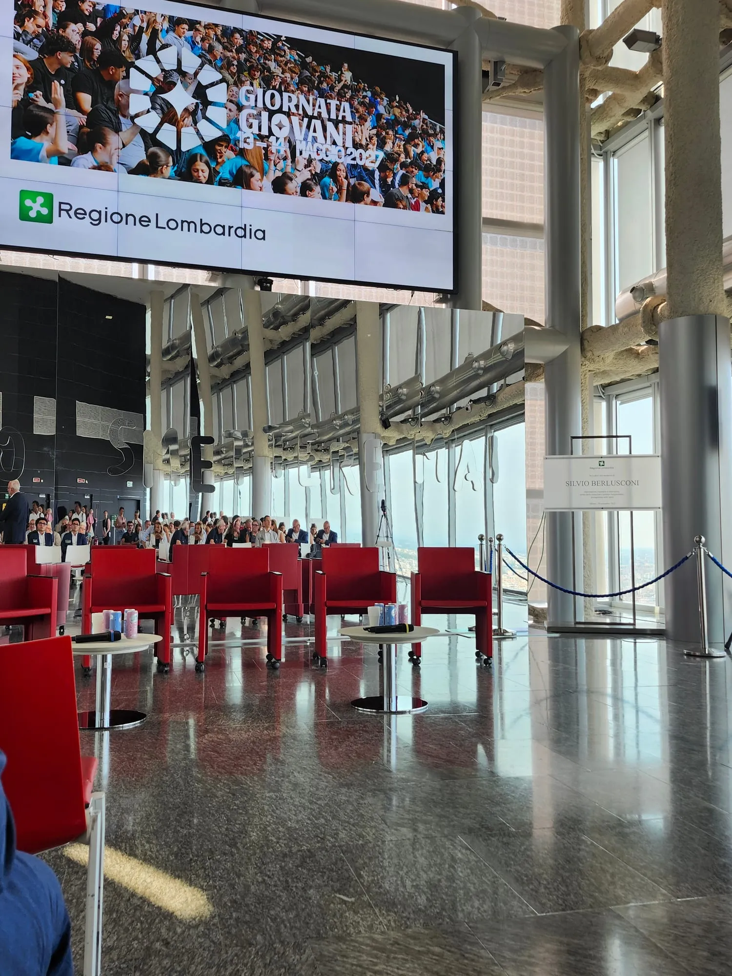 La sala al 39° piano prima dell'inizio: poltrone rosse, lo schermo acceso e le vetrate sulla città