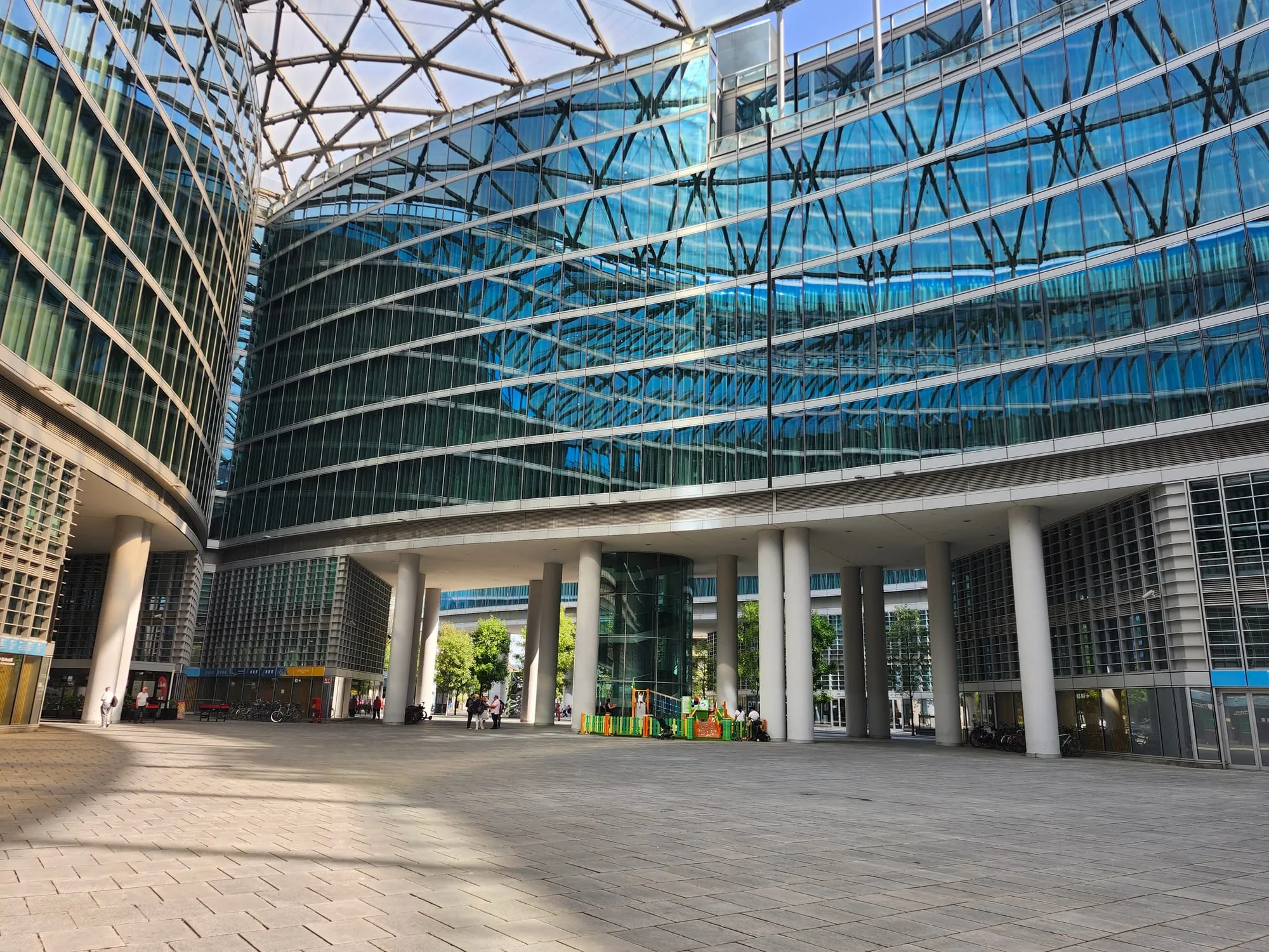 La piazza coperta di Palazzo Lombardia, con la facciata curva a vetri e la volta reticolare