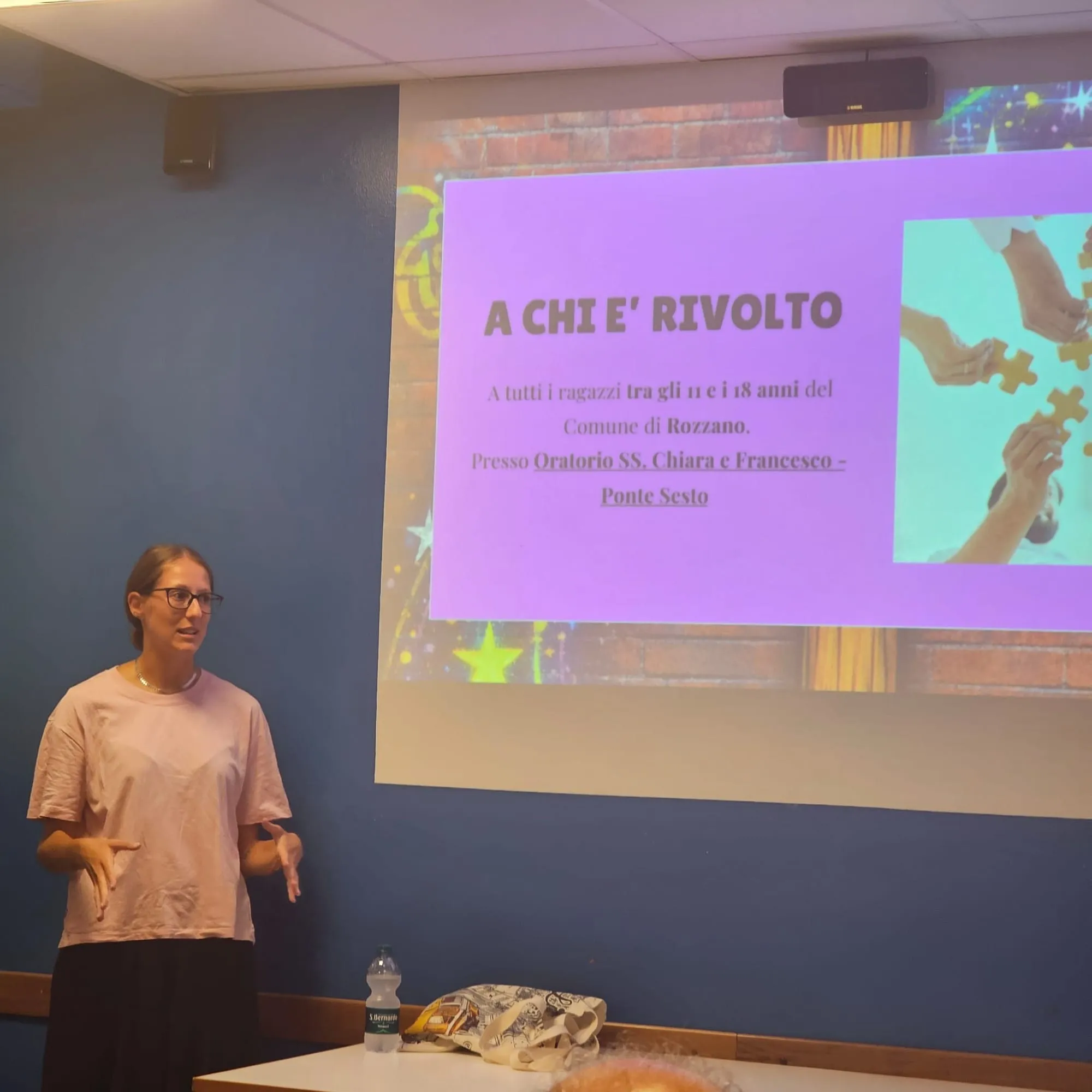 Una delle relatrici davanti alla slide «A chi è rivolto»: ai ragazzi fra gli 11 e i 18 anni del Comune di Rozzano, presso l'Oratorio SS. Chiara e Francesco di Ponte Sesto
